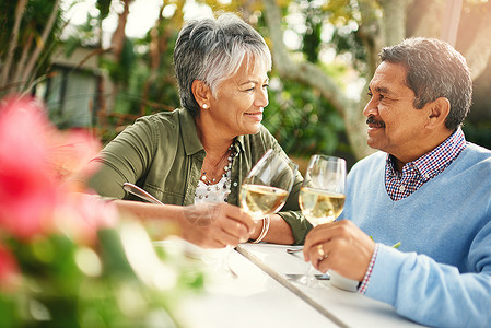 与你相伴的每一秒都是庆祝的理由 一对快乐的老夫妇在户外午餐时一起喝杯酒背景图片