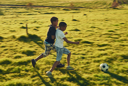 被踢足球和朋友一起玩足球 被射中了两个孩子 在外边的田野里一起踢足球背景