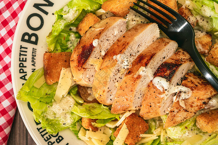 凯撒沙拉配切成薄片的鸡胸肉和传统的蒜泥蛋黄酱 盘子上写着“” 顶视图 特写细节背景图片