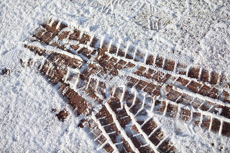 城市人行道上软雪上的新鲜轮胎痕迹高清图片