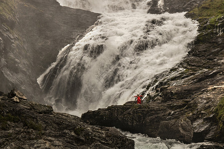 与Kjosfossen瀑布的水跳舞红色舞蹈女士岩石背景图片