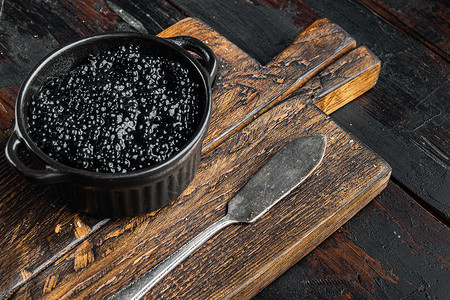 黑色鱼子酱 在旧黑木桌背景上深色美味胡索白鲸木质玻璃桌子海鲜背景图片