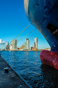 杂货船鹿特丹摩天大楼从停泊在Nieuwe Maas河码头的货船下背景