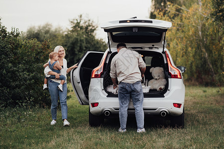 带车素材两位父母带着他们的小孩准备在户外野餐 年轻的家庭在 SUV 车上享受公路旅行背景