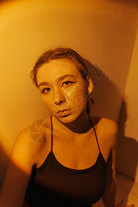 一位年轻女性的短光肖像眼睛长发梦幻金发聚光灯女士橙子工作室化妆品马尾辫背景图片