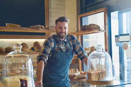 一个年轻的商业老板站在面包店柜台后面的肖像 他当时在面包店里做客背景图片