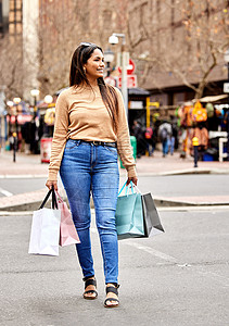 周末优惠购她在寻找超值优惠 一个迷人的年轻女人在城市购物时背着一堆袋子的全长镜头背景