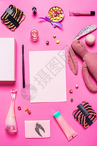 粉红背景的女孩的饰品香水指甲油兔子手镯衣服唇线糖果贸易化妆品时尚背景图片