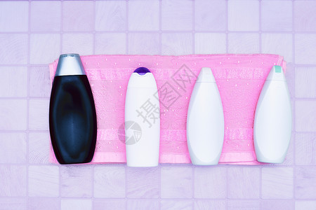 四瓶洗涤剂和香水的塑料瓶 粉红背景的毛巾背景图片