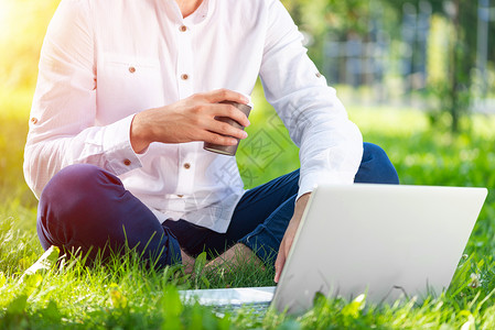 商务人士在绿草上使用膝上型计算机场地电脑杯子笔记本博客键盘技术闲暇男性工作背景图片