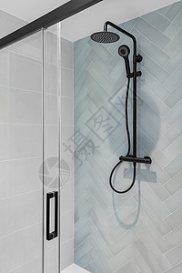 现代淋浴带雨头 手握淋浴和玻璃门 浴室有浅蓝白瓷砖高清图片
