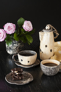 两杯黑咖啡 黑色巧克力 一个黄茶壶和一个花瓶 底底有粉红玫瑰咖啡机黄色休息玫瑰餐巾杯子坚果早餐背景图片