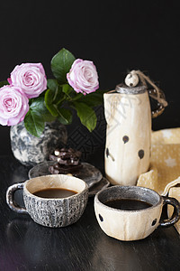 两杯黑咖啡 黑色巧克力 一个黄茶壶和一个花瓶 底底有粉红玫瑰玫瑰黄色坚果咖啡机杯子早餐餐巾休息背景图片