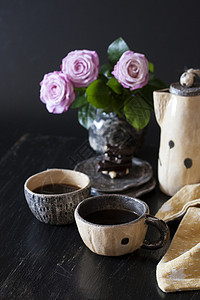 两杯黑咖啡 黑色巧克力 一个黄茶壶和一个花瓶 底底有粉红玫瑰餐巾玫瑰杯子坚果黄色休息咖啡机早餐背景图片