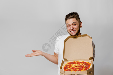 有披萨的英俊快递 指向空旷的文字广告空间 从餐厅安全送货 自信的学生会做信使工作潮人快乐盒子办公室远程男人食物商务人士背景图片