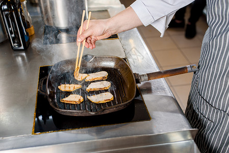 煎锅里炸鸡肉片 煮拉面汤 厨师用日本棍棒接鸡做饭背景图片