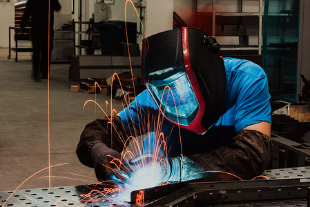 训练面具在工厂内工作的专业重工业焊工 戴着头盔并开始焊接 选择性焦点工程车间维修工程师机器培训技术商业工业安全背景