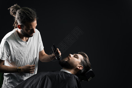 在理发店刮胡子 长着脚镣的理发师修剪英俊胡子的男人头发工作室男性剃刀店铺理发剃须顾客绅士主义背景图片