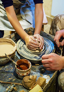 做陶器主人和学生的手在黄色粘土的波特车轮上做一个投手 有选择地集中注意力于手水壶工匠雕塑创造力制品杯子雕塑家爱好工作车轮背景