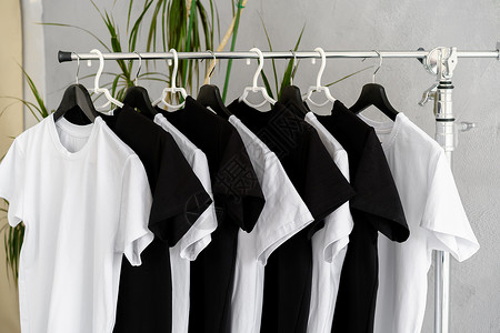 服装推广素材挂在架子上的黑白T恤推介会织物纺织品黑色服装衣服打印推广品牌白色背景