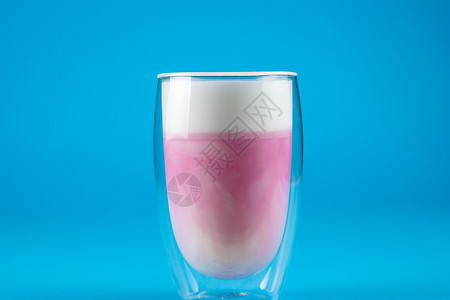 蓝色背景的皮塔哈亚粉红色火柴 龙果鸡尾酒配双杯玻璃杯粉色玻璃酒精泡沫奶昔抹茶拿铁饮料白色牛奶背景