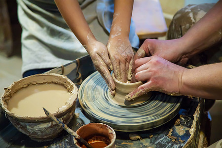 做陶器主人和学生的手在黄色粘土的波特车轮上做一个投手 有选择地集中注意力于手爱好模具水壶雕塑车轮雕塑家黏土陶瓷造型艺术家背景
