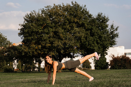 在公园绿草上对女孩进行适合的训练 户外锻炼 活跃青年妇女的体育生活方式太阳力量健身房女性身体街道运动运动装功能女士背景图片