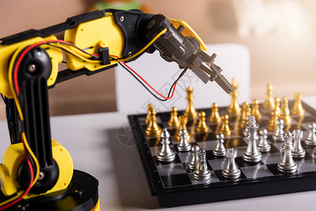 特写黄色机器人臂 在棋盘上下棋学校机械汽车手臂商业典当机器游戏科学实验室背景