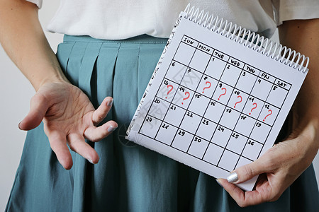女人拿着日历 明显错过了月经 意外怀孕 妇女健康和月经延迟背景图片