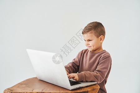 家庭教育公益讲座英俊的孩子使用笔记本电脑 看着相机 观看虚拟讲座和教程 电子学习和知识 准备课程和在白色背景下在线学习家庭教育职场工具学校社会网背景