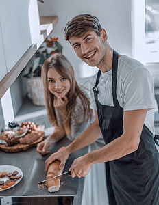 年轻情侣为早餐做三明治很快乐男性烹饪桌子美食夫妻面包闲暇房子微笑家庭背景图片