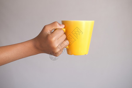 手举着黄色杯子的人创造力享受咖啡男人黑色背景图片