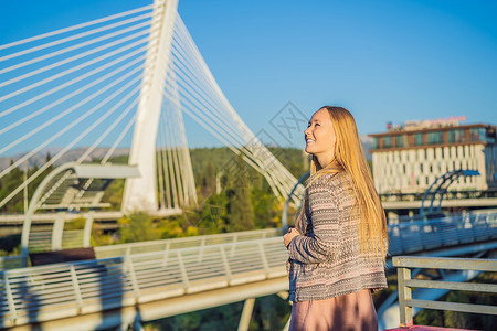 波德戈里察莫斯科人行天桥背景下的女游客 这座人行天桥的金属结构是莫斯科市送给黑山人民的礼物 建于 2008 年 现代设计与附近的背景图片