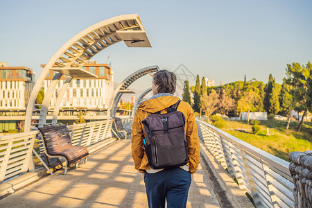 波德戈里察莫斯科人行天桥背景下的男游客 这座人行天桥的金属结构是莫斯科市送给黑山人民的礼物 建于 2008 年 现代设计与附近的背景图片