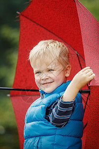 一个小男孩的红色大雨伞形象 垂直照张照片图片