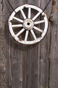 挂在谷仓墙上的旧木制车轮圆圈古董车皮教练日志先锋乡村农业轮缘金属背景