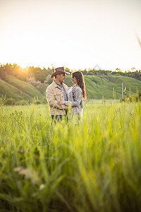 年轻美人夫妇 站在绿草地上 在落日的光线下 牛仔服装 风流风格裙子女孩新娘订婚男性庆典婚礼花束婚姻乡村图片