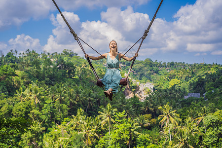 绳索摆动年轻女子在印度尼西亚巴厘岛的丛林雨林中荡秋千 在热带摇摆 秋千巴厘岛的潮流绳索环境海滩旅行顶峰瀑布天空座位青少年女孩背景