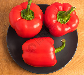 保加利亚语木板上黑色盘子里的三片甜辣椒作品营养白色小吃蔬菜团体食物美食绿色红色背景