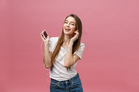生活方式概念 年轻女性使用电话收听粉红背景音乐的青春妇女耳机女孩歌曲闲暇收音机女士技术享受手机工具背景图片