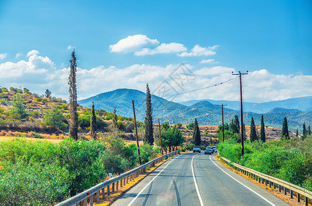 特罗多斯塞浦路斯地貌景观 车辆在河谷的沥青路上行驶 有黄色干燥田 树和路边杆土地曲线农村风景蓝色汽车骑术旅行两极天空背景