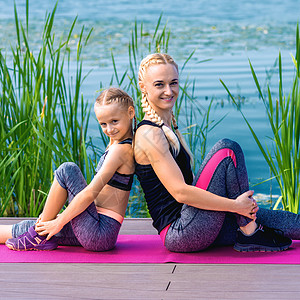 教练型父母母亲和女儿坐在瑜伽垫上的肖像生活方式成人家庭女性孩子教练火车父母女孩运动装背景