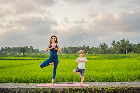 做运动男孩男孩和他的瑜伽老师 在稻田做瑜伽团体童年健身房姿势运动体操公园沉思身体女士背景