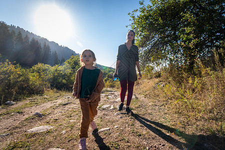 一个年轻母亲和她女儿5岁的女儿在山上散步 女孩像马一样用棍棒子幸福高清图片素材