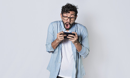 男人横着拿着手机 盖伊喘着粗气用智能手机玩游戏闲暇眼镜电话个性时刻背景图片