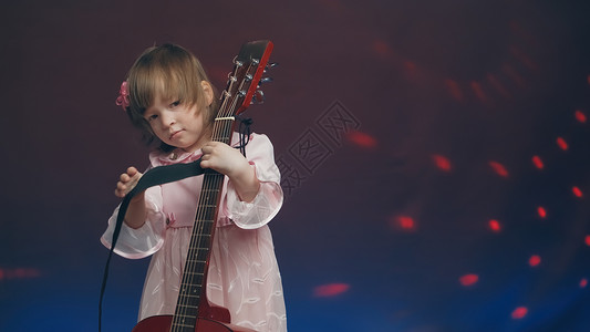 穿粉红旧礼服的小女孩 像双低音一样弹声吉他大提琴音乐会中提琴青年宝宝裙子才俊家庭彩色舞蹈背景图片