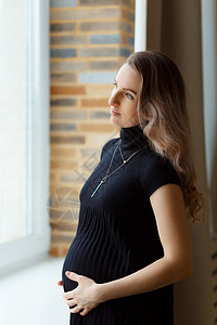 深思熟虑的孕妇抚摸她的肚子母亲窗户生活幸福怀孕女性女孩婴儿妈妈家庭背景图片