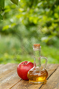 甜醋玻璃瓶中的苹果醋和木板上新鲜的红苹果桌子食物水果玻璃果汁红色绿色液体瓶子乡村背景