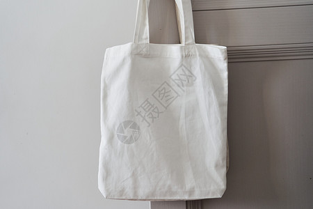 手提袋模板白色生态友好袋挂在门把手上 罐装袋帆布购物织物女性小样礼物材料棉布顾客手提包背景