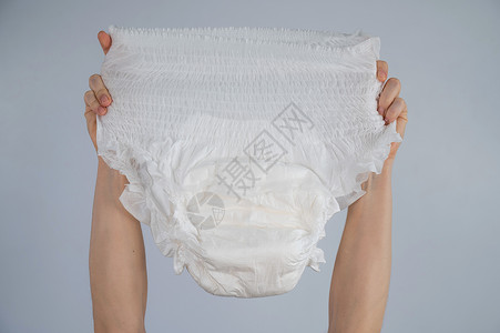 白色内衣一个女人拿着白色背景的成人尿布 尿失禁问题内衣吸收失智苗圃织物棉布卫生餐巾服装吸水性背景